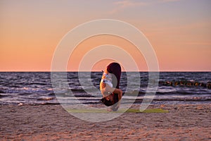Young woman doing yoga by the sea
