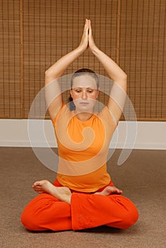 Young woman doing yoga in the sunny room