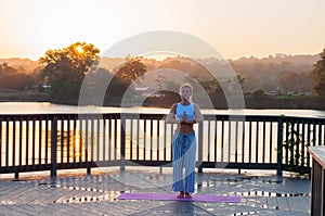 Young woman is doing yoga on the sunrise