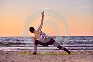 Young woman doing yoga at sunset