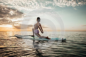 Young woman doing YOGA on a SUP board in the lake