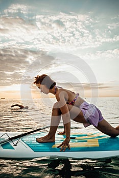 Young woman doing YOGA on a SUP board in the lake