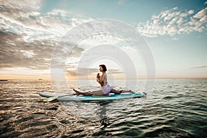 Young woman doing YOGA on a SUP board in the lake
