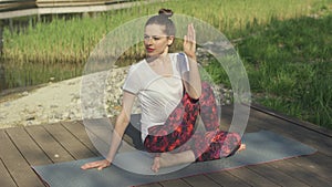 Young woman doing yoga twist in park