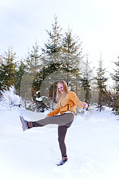 Young woman doing yoga in winter forest. Healthy lifestyle and sport concept