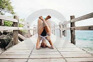 Young woman doing yoga on the wooden bridge photo