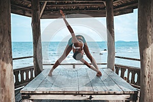 Young woman doing yoga in the wooden gazebo at the beach