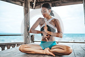 Young woman doing yoga in the wooden gazebo at the beach