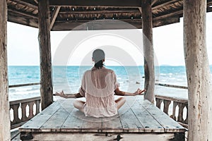 Young woman doing yoga in the wooden gazebo at the beach