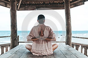 Young woman doing yoga in the wooden gazebo at the beach