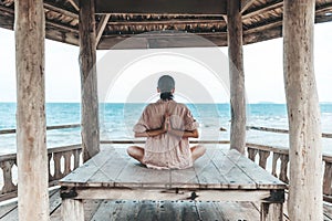 Young woman doing yoga in the wooden gazebo at the beach