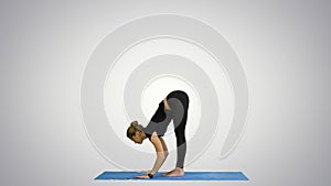 Young woman doing yogic sun salutation pose on mat on white background