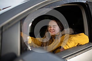 Young woman with Down syndrome driving a car and smiling.
