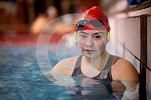 Young woman with Down syndrome in swimming pool looking at camera