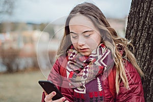 Young woman with Down syndrome walking in street in winter and using smartphone