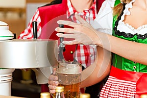 Young woman drawing beer in restaurant or pub