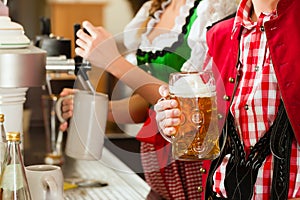 Young woman drawing beer in restaurant or pub