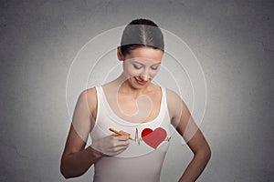 Young woman drawing a heart on her t-shirt