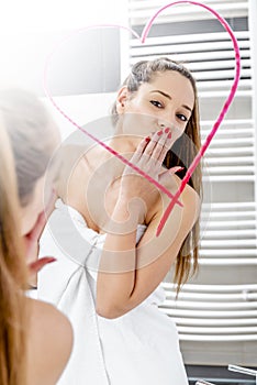 Young woman drawing heart to the mirror