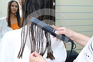 Young woman with dreadlocks. false dreadlocks on the curling iron