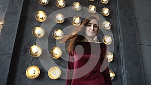 Young woman in dress and beautiful face on a background of wall with powerful lamps