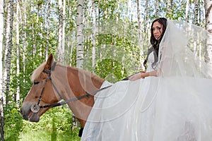 Young woman in the dress of fiancee on a horse