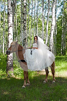 Young woman in the dress of fiancee on a horse