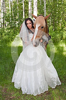 Young woman in the dress of fiancee next to a horse