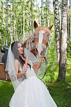 Young woman in the dress of fiancee next to a horse