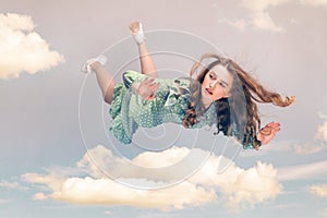 Young woman in dress flying in the sky.