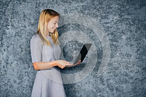 Young woman in dress with laptop over gray background