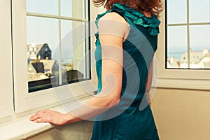 Young woman in dress looking out the window