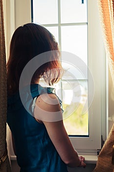 Young woman in dress looking out the window