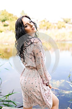 young woman in dress standing near river on natural sunset background  vertical picture