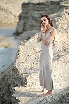 Young woman in dress standing on sand near sea