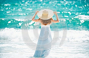 Young woman in dress on tropical beach. Beautiful girl on summer vacation. Tanning concept. Happy traveller woman in