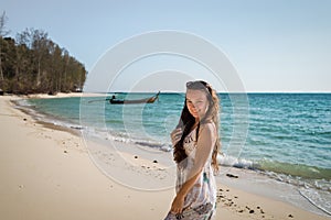 Young woman in dress is walking on the beach on the coast of the ocean