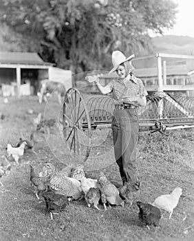 Young woman dressed as a farmer bringing food to the chicken