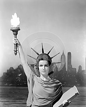 Young woman dressed as the Statue Of Liberty with skyscrapers in the background