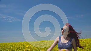 Young woman dressed in boho style swaying in the middle of green wheat field is catching wind blowing close her eyes to