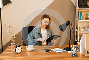 Young woman dressed casual working digital tablet. Business woman busy working on digital tablet at home office.