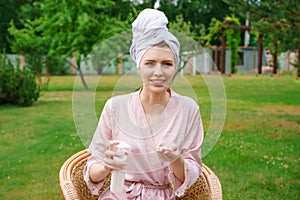 Young woman dressed for shower towel wrapped head for hair hold in bottles