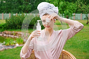 Young woman dressed for shower towel wrapped head for hair hold in bottles