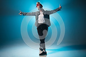 Young woman hip-hop dancer on studio blue light background with flare effects