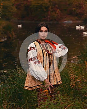 Young woman dressed traditional ukrainian embroidered clothes. Portrait of beautiful confident girl with long dark hair and brown