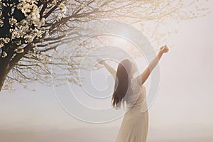 young woman dressed in white taking a breath in the middle of spring nature