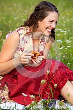 Young woman in drindl sitting in a meadow and laughing