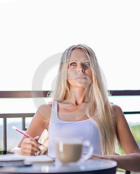 Young woman drink coffee and writing in note book journal in cafe