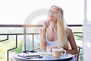 Young woman drink coffee and writing in note book journal in cafe