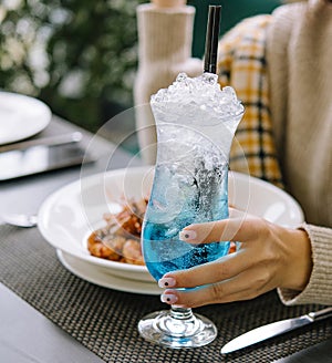 young woman drinking blue lagoon cocktail